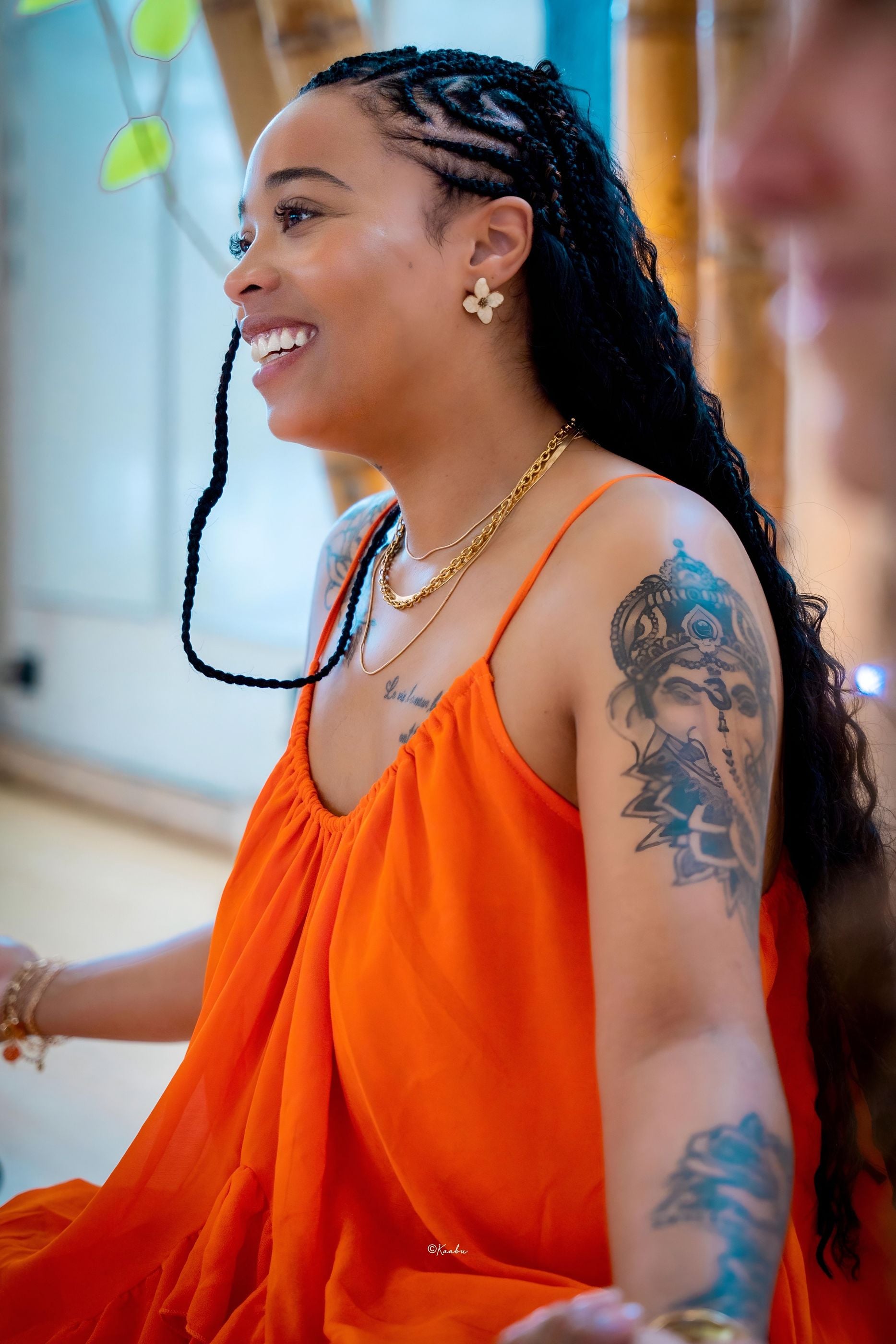 Océane, en robe orange, sourit, tournée vers quelqu’un